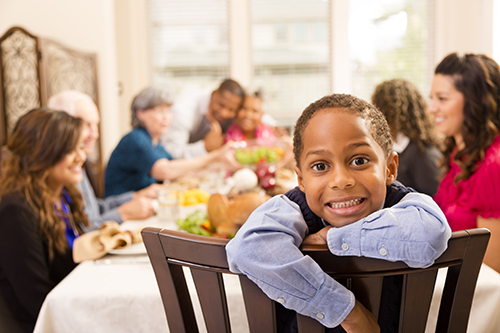 A family gathers around the table at Thanksgiving dinner.