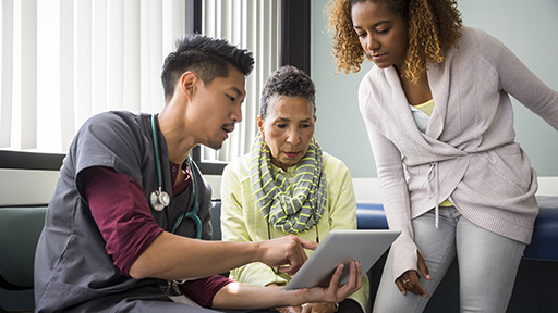 Doctor helping patient sign consent form on tablet